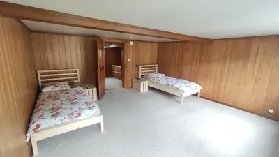 two beds in a room with wooden walls at romatisches Chalet mit Bodenseesicht in Wolfhalden
