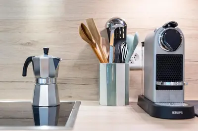 a kitchen counter with a coffee maker and utensils at Modernes Apartment mit Balkon und Parkplatz, Nähe See in St. Gallen