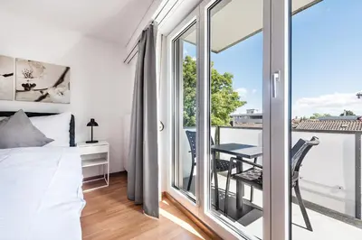 a bedroom with a bed and a balcony with a table at SOHO 4B !Gratis Parken, Free Parking! in Kreuzlingen