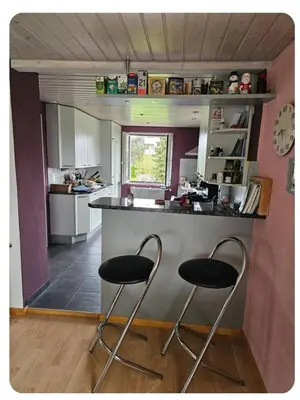a kitchen with two bar stools at a counter at Holzchalet mit Garten in Egnach