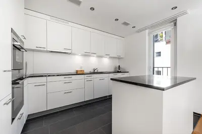 a kitchen with white cabinets and a black counter top at DESIGN-APARTMENT 1 !Gratis parken, Free Parking! in Kreuzlingen