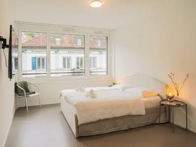 a white bedroom with a large bed and two windows at Stilvoll & zentral in St Gallen -WYBA Living Rio in St. Gallen