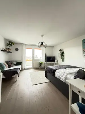 a bedroom with a large bed and a couch at HRE Apartments Lago Rorschach in Rorschach
