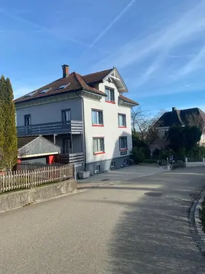 a white house with a brown roof on a street at Dachwohnung in Niederuzwil