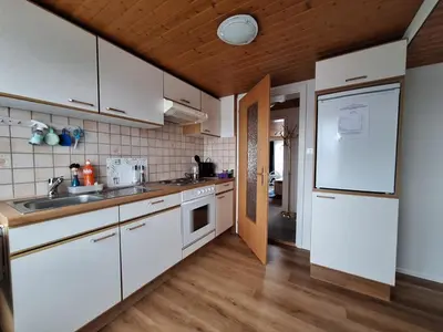 a kitchen with white cabinets and a white refrigerator at Dachwohnung in Niederuzwil