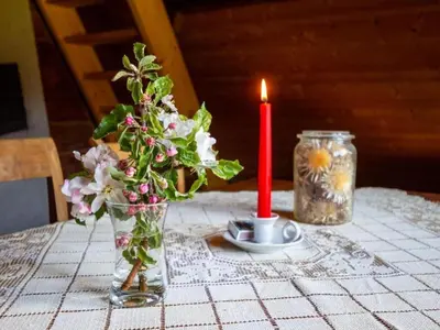 a candle and a vase with flowers on a table at Holiday Home Fromsenrüti by Interhome in Walzenhausen