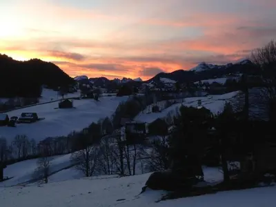 a sunset over a snow covered mountain with a town at Holiday Home Neuer Sigerst by Interhome in Wildhaus