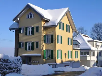 a yellow house with snow on the roof at Apartment Rätia by Interhome in Wolfhalden