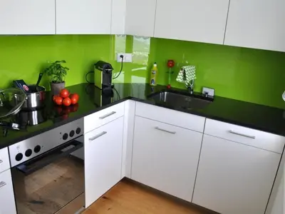 a kitchen with white cabinets and green walls at Apartment Rätia by Interhome in Wolfhalden