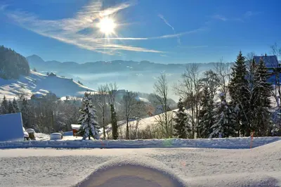a snow covered slope with the sun in the sky at Sonnmatt Bergpension & Gesundheitszentrum in Ebnat