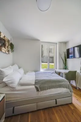 a white bedroom with a large bed and a window at Urban Hideaway Studio St Gallen Center in St. Gallen