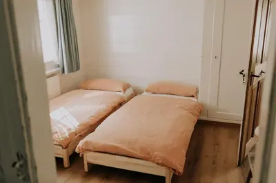 two beds in a small room with a window at Zimmer Alpstein im Appenzeller Ferienhaus in Brülisau