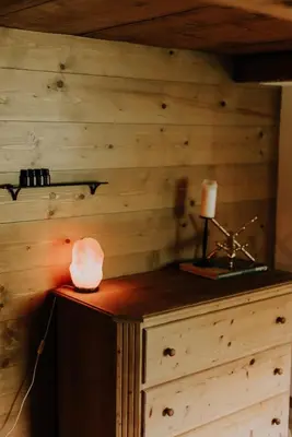 a room with a wooden wall with a lamp and a candle at Zimmer Alpstein im Appenzeller Ferienhaus in Brülisau