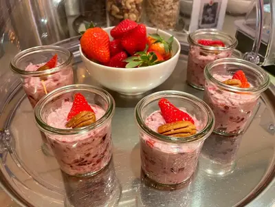 a tray with four glasses of strawberry chia pudding and a bowl of strawberries at Hotel Garni Rössli in St. Gallen