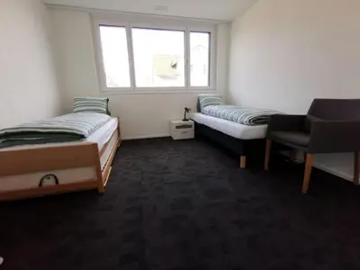 a room with two beds and a chair and a window at Apartment HIRSCHEN by Interhome in Gossau