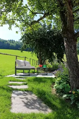 a park bench sitting on a walkway next to a tree at Apartment Vordere Au by Interhome in Schwellbrunn