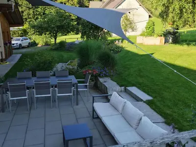 a patio with a white couch and tables and an umbrella at Apartment Bauernhaus VordereAu by Interhome in Schwellbrunn