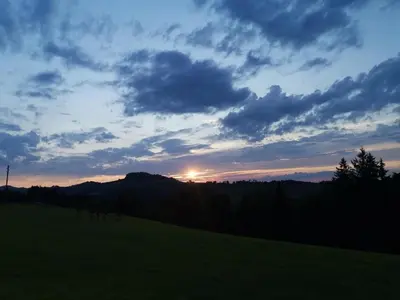 a sunset on a hill with a green field at Apartment Tiererlebnishof Windegg by Interhome in Urnäsch