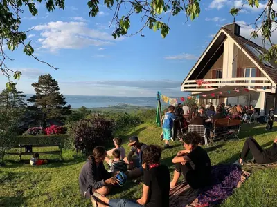 a group of people sitting on the grass in front of a barn at Holiday Home See in Sicht by Interhome in Wolfhalden