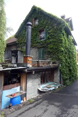 an ivy covered house with a building with a window at Holiday Home das schiefe Haus by Interhome in Oberschan