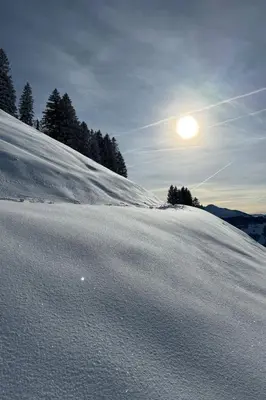 a snow covered hill with the sun in the sky at Apartment Zwingli's Ferienwohnung by Interhome in Nesslau