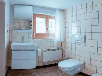 a bathroom with a toilet and a sink and a window at Holiday Home Alpenrösli in Nesslau by Interhome in Nesslau
