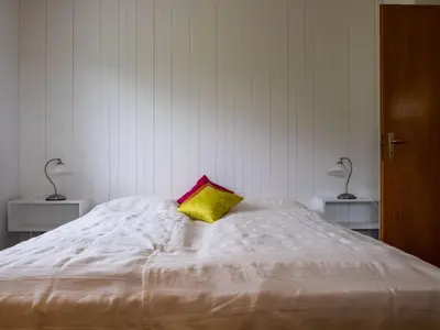 a white bed with a yellow pillow on top of it at Holiday Home Haus am Schwendisee by Interhome in Wildhaus