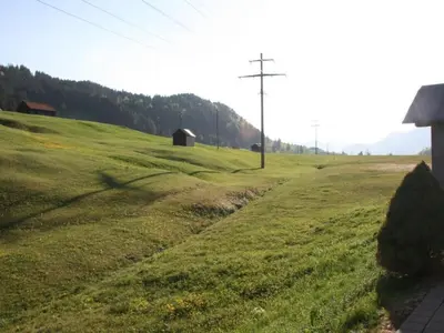 a field of green grass with a barn in the distance at Apartment Bädli by Interhome in Wildhaus