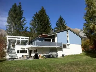 a white house with a porch and a lawn at Holiday Home Befang 17 by Interhome in Wildhaus
