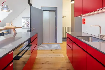 a kitchen with red cabinets and a sink at BLIV Exklusive Dachgeschosswohnung im Zentrum in St. Gallen