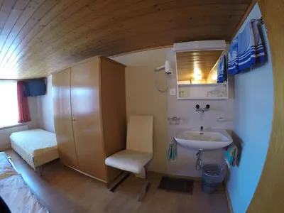 a small bathroom with a sink and a chair at Hotel Garni Traube B&B in Schwellbrunn
