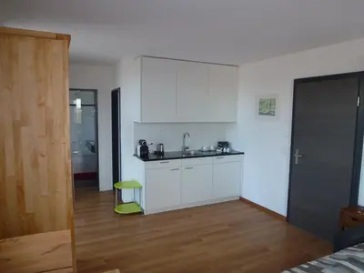 a kitchen with white cabinets and a green stool at Hotel Enjoy in Goldach