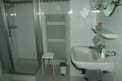 a white bathroom with a sink and a shower at Hotel Pension Im Dorf in Zuzwil