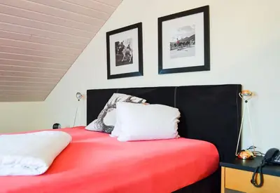 a bedroom with a red bed with two white pillows at Hotel Landhaus Säntis Herisau in Herisau