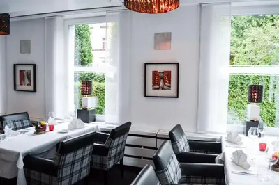 a restaurant with white tables and chairs and windows at Hotel Landhaus Säntis Herisau in Herisau
