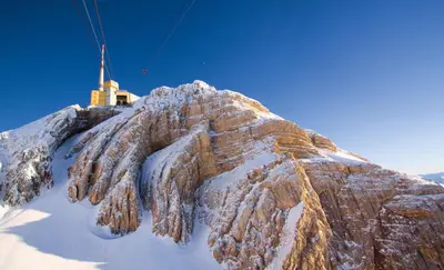 a mountain covered in snow with a tower on top at Hotel Landhaus Säntis Herisau in Herisau