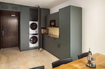 a kitchen with a table and a washer and dryer at b-smart hotel Widnau in Widnau