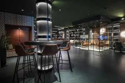 a restaurant with a round table and chairs and lights at Revier Hotel Säntispark in St. Gallen