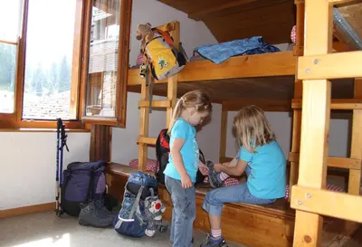 two girls sitting on a bench in a bunk bed at Berghotel Sellamatt in Alt Sankt Johann