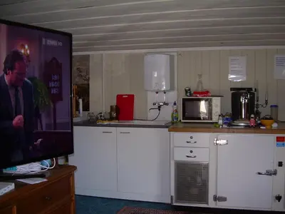 a kitchen with white cabinets and a flat screen tv at Wohlfühloase für Mensch und Hund in Uzwil