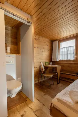 a bedroom with a bed and a desk and a table at Gasthaus Rössli in Mogelsberg