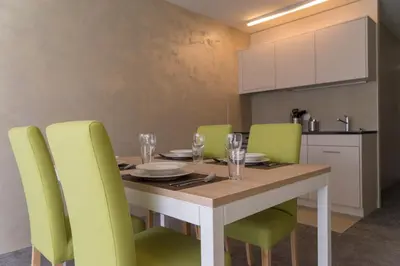 a dining room table with green chairs around it at wohnMOTEL - Hinterforst in Altstätten