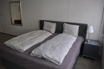 a bed with gray sheets and pillows on it at Loft AR in Bühler