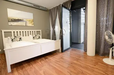 a bedroom with a white bed and a wooden floor at Berger Zentrum in Berg