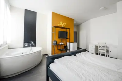 a bedroom with a tub and a bed and a television at Berger Zentrum in Berg