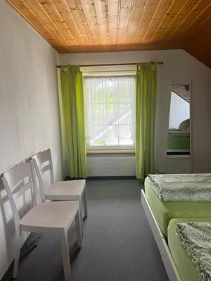 a room with two beds and a window with green curtains at Sitter-Panorama in Bischofszell
