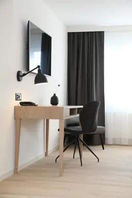 a desk with a lamp and a chair in a room at Businesshotel Forum Widnau in Widnau