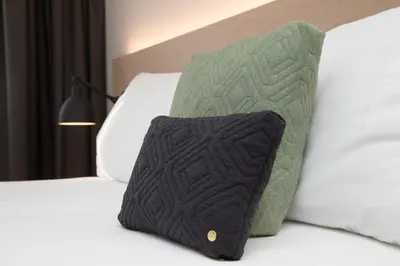 a black and green pillow on a bed at Businesshotel Forum Widnau in Widnau