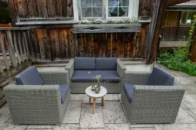 three wicker chairs and a table on a patio at Ferienhotel Idyll Gais in Gais