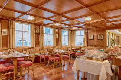 a dining room with tables and chairs and windows at Hotel Hecht in Appenzell